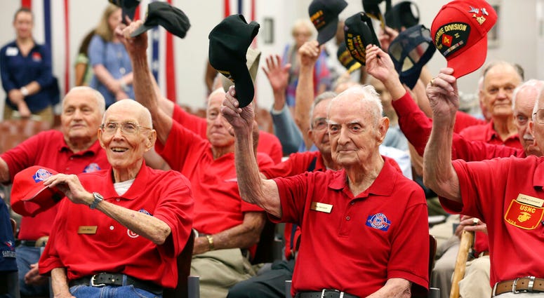 World War II veterans salute with their caps as they pose for a photograph after a ceremony at Joint Base San Antonio-Fort Sam Houston