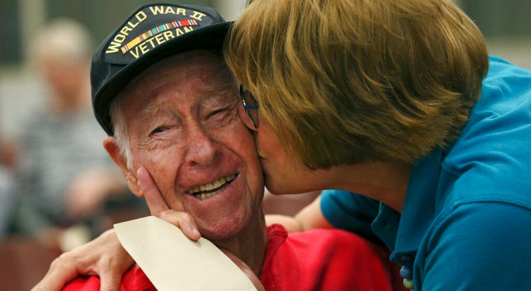 Alamo Honor Flights volunteer Elizabeth Montalvo kisses World War II veteran E.W. King, 94, before a ceremony