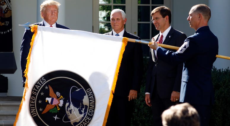 President Donald Trump watches with Vice President Mike Pence and Defense Secretary Mark Esper as the flag for U.S. space Command is unfurled as Trump announces the establishment of the U.S. Space Command in the Rose Garden of the White House. President Trump watches as the Space Command flag is unfurled at the White House.