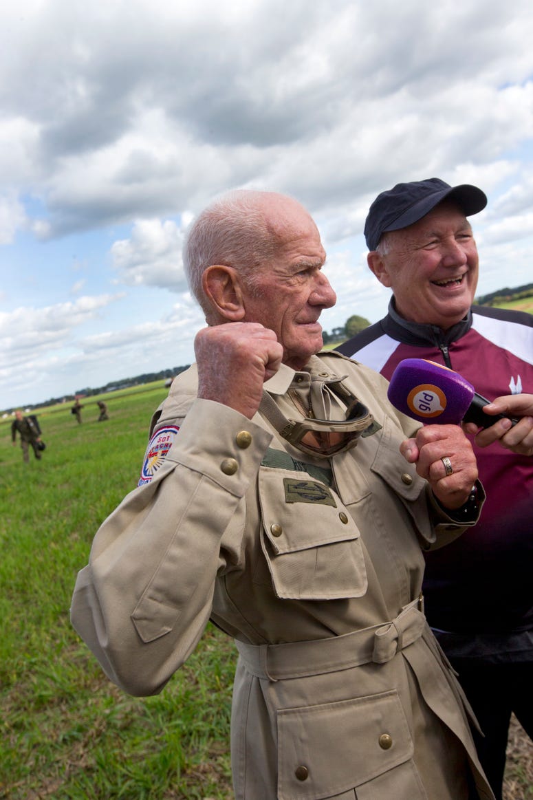 Tom Rice, a 98-year-old American WWII veteran, and U.S. Ambassador Pete Hoekstra, right, talk to journalists after landing with a tandem parachute jump near Groesbeek, Netherlands, Thursday, Sept. 19, 2019. 98 year old veteran talks to reporters after jumping out of plane to commemorate DDay.