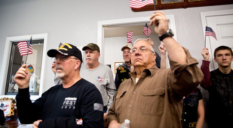 In this Saturday, Jan. 4, 2020, file photo, veterans, family members, guests and volunteers raise American flags during the official grand opening of New Freedom Farm in Buchanan, Va. New Freedom Farm