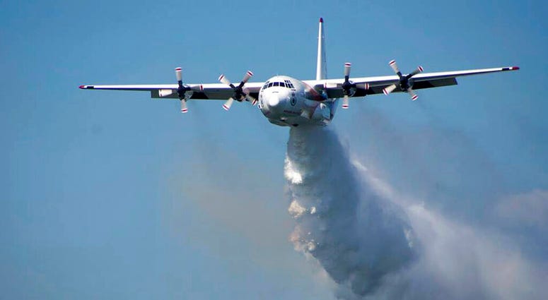 In this undated photo released from the Rural Fire Service, a C-130 Hercules plane called "Thor" drops water during a flight in Australia.