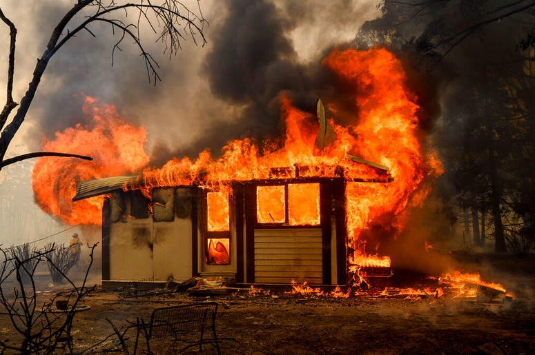 In this Thursday, Jan. 23, 2020, file photo, a firefighter battles the Morton Fire as it consumes a home near Bundanoon, New South Wales, Australia.