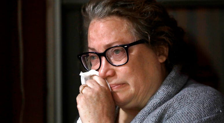 Susan Kenney, of Ware, Mass., who lost her father to the coronavirus, is tearful while speaking to a reporter from The Associated Press