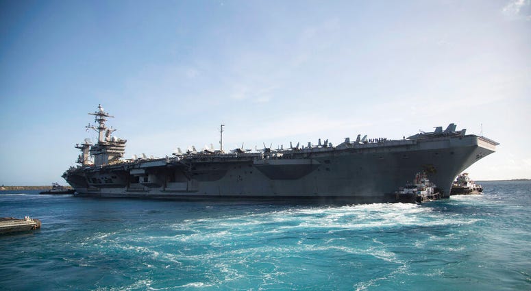 In this photo provided by the U.S. Marine Corps, the aircraft carrier USS Theodore Roosevelt (CVN 71) departs Apra Harbor at Naval Base Guam on Thursday, May 21, 2020