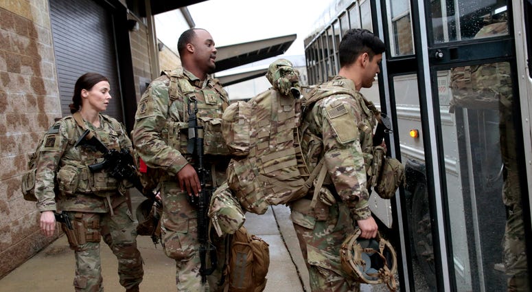 U.S. Army soldiers with their gear board an awaiting bus at Fort Bragg, N.C.