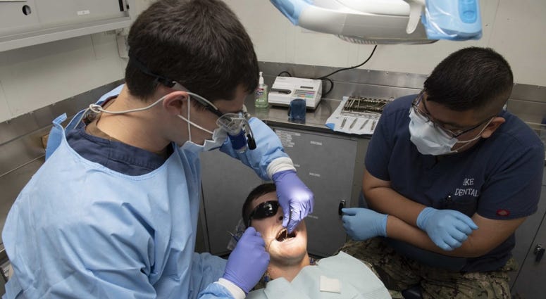 Lt. Conrad Schulte, from Grants Pass, Oregon, left, and Hospital Corpsman 3rd Class Manuel Perez, from San Benito, Texas, perform a dental examination aboard the aircraft carrier USS Dwight D. Eisenhower (CVN 69). Military-dental
