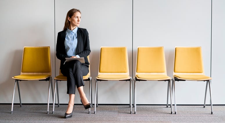 Young woman sitting in lobby with resume in hands and waiting for job interview