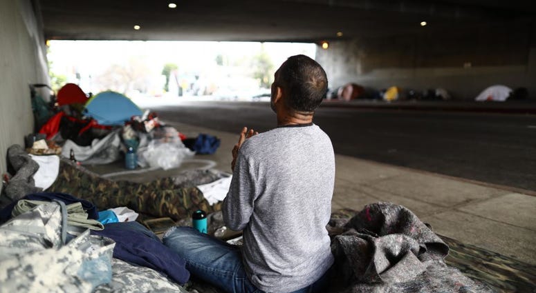 Travis Stanley, who said he has been homeless for three months and is a U.S. Navy veteran, sits on donated bedding, where he normally sleeps, beneath an overpass on June 5, 2019 in Los Angeles, California. Homeless