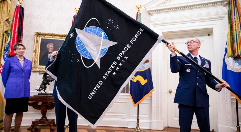 Gen. Jay Raymond (R), Chief of Space Operations, and CMSgt Roger Towberman (L), with Secretary of the Air Force Barbara Barrett present US President Donald Trump with the official flag of the United States Space Force in the Oval Office of the White House SpaceForceFlag