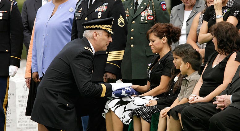 US Army Brigadier General Bennett Sacolick (L) presents a folded American flag to Sgt. Charles Wyckoff's widow Erika Wyckoff during his funeral at Arlington National Cemetery June 15, 2007. GoldStarFamily