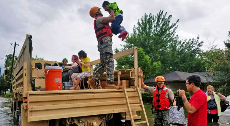 National Guardsmen assist residents affected by flooding caused by Hurricane Harvey onto a military vehicle August 27, 2017 in Houston, Texas. NationalGuard
