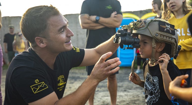 A reconnaissance team leader course instructor assists Haven Tablada with reconnaissance gear after a raid demonstration during the annual Gold Star Family retreat, Marine Corps Training Area Bellows, May 4, 2019. GoldStarFamily