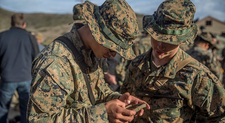 Marines with Kilo Company, 3rd Battalion, 4th Regiment, 1st Marine Division, look at an Android phone with enhanced Beartooth radio capabilities, which allow them to talk, text, and see teammates on a map without requiring cellular service or Wi-Fi, durin