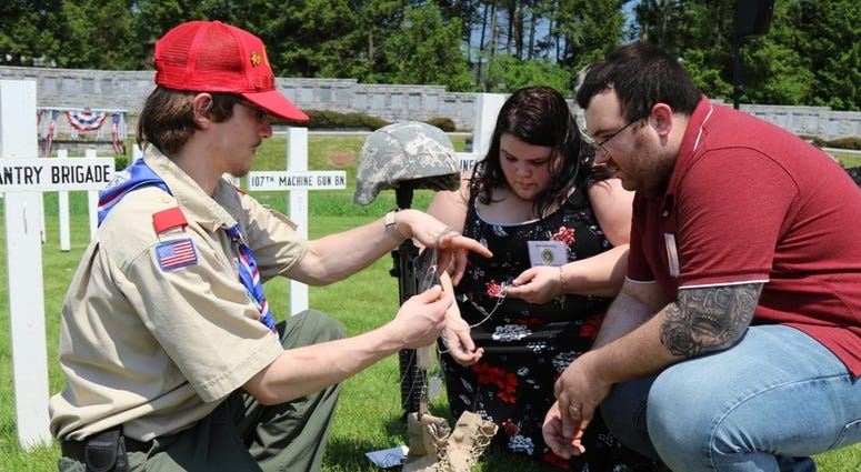 Dakota Bickel of Shirleysburg, a Boy Scout with Juniata Council Troop 237, helps Danielle and Ron Clay of Indiana, Pa. find an identification tag for Danielle’s uncle, Sgt. 1st Class Randy McCaulley, who was killed March 23, 2006 in Afghanistan. The scout 28 Infantry Division Annual Memorial Service