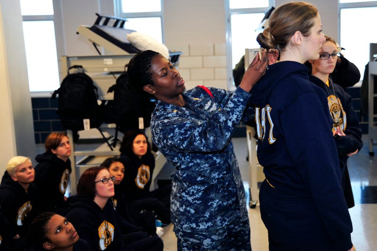 Chief Logistics Specialist Natali Philip (left), a recruit division commander (RDC), uses a ruler to measure the hair of Seaman Recruit Briana Cochems, from Los Angeles, to show proper hair grooming standards to new recruits at Recruit Training Command