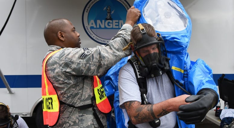 U.S. Air Force Airman David Schroyer, right, an emergency management specialist with the 118th Civil Engineer Squadron, Tennessee Air National Guard, gets help putting on a hazardous materials suit from Senior Airman Omar Lewis, ToxicExposure