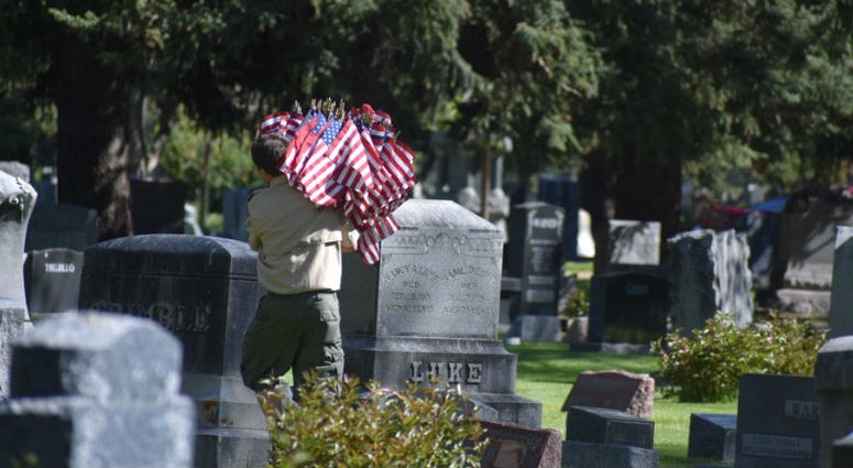 A Boy Scout caries flags through Grandview Cemetery in Fort Collins, Colorado. Memorial Day weekend across America.