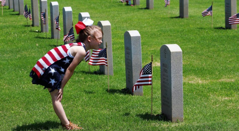 Adilynn Poteet, 6, reads the inscription on a headstone after Monday's Memorial Day ceremony at Texas State Veterans Cemetery at Abilene. Memorial Day weekend across America.