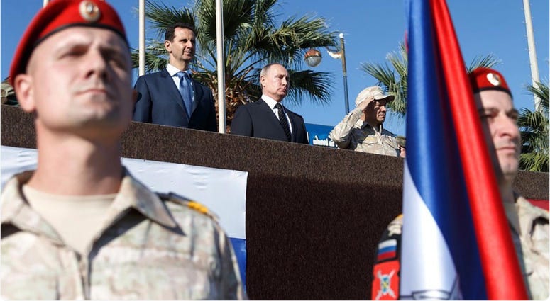 Syrian President Bashar al-Assad (1st L, Rear) and his Russian counterpart Vladimir Putin (2nd L, Rear) view a military parade in the Russian-run Hmeimim Air Base in the coastal city of Latakia, Syria, on Dec. 11, 2017. assad