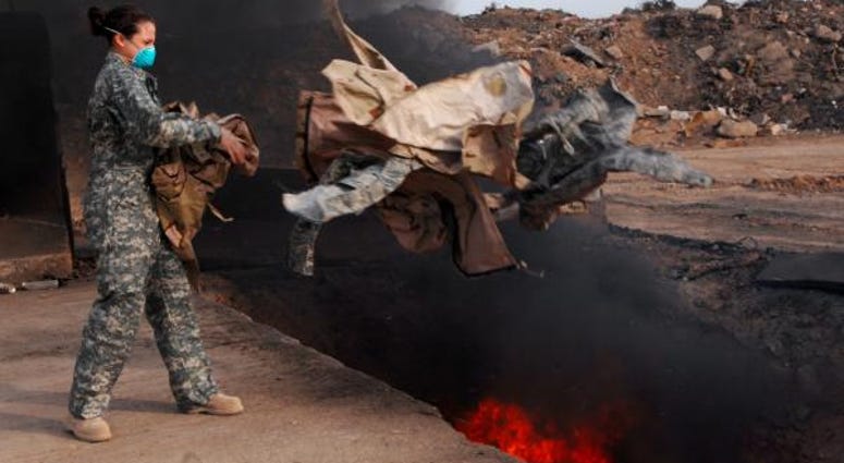 Senior Airman Frances Gavalis of the 332nd Expeditionary Logistics Readiness Squadron tosses unserviceable uniform items into a burn pit in Balad, Iraq, March. 10, 2008. burn