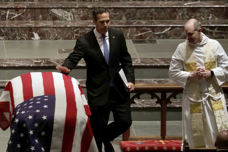 George P. Bush touches the flag-draped casket of his grandfather, after delivering an eulogy at the funeral of former President George H.W. Bush in Houston, Texas.