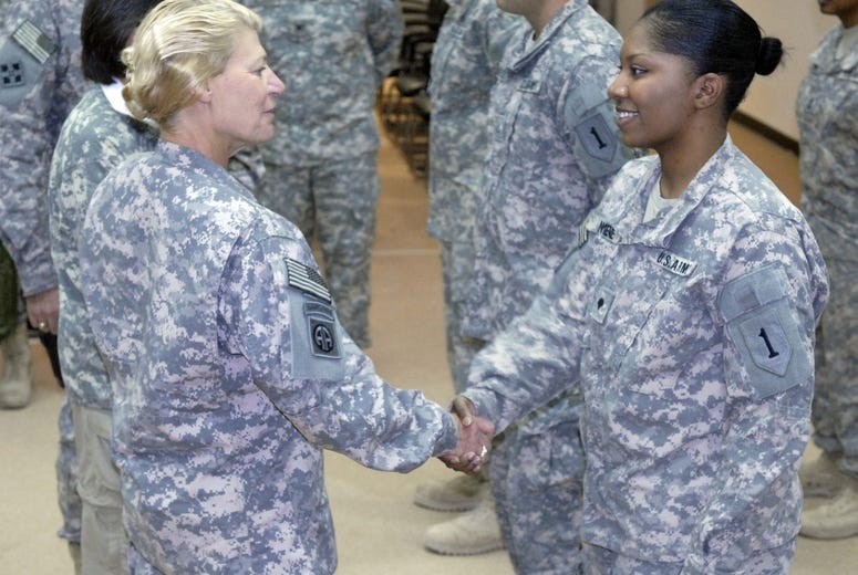 Gen. Ann E. Dunwoody, commander of U.S. Army Materiel Command and the first female four-star general in Army history (center), presents a coin to Spc. Bryanna Nimene, a medic with 299th Brigade Support Battalion.