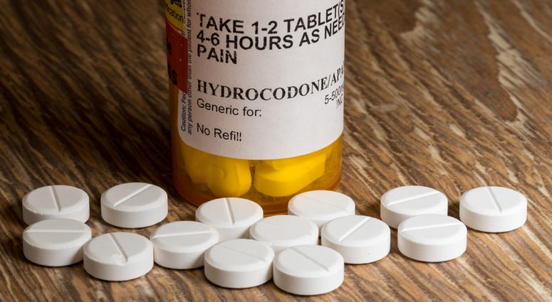 Close photo of prescription bottle for Hydrocodone tablets and pills on wooden table. hydrocodone