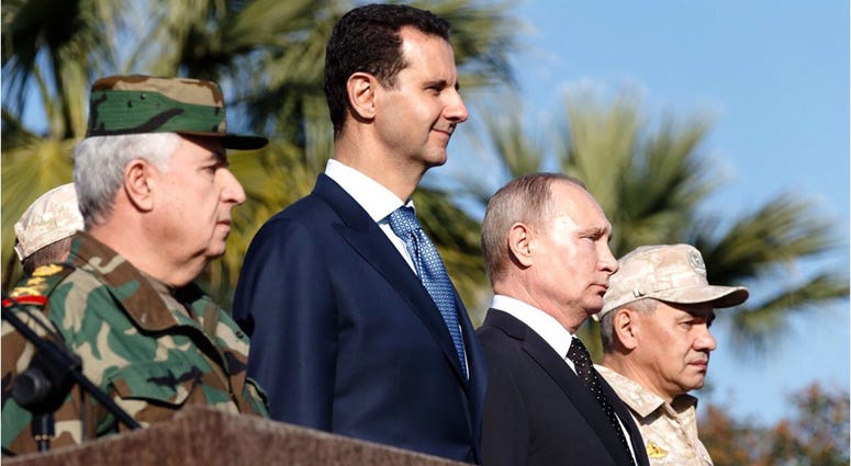 Syrian President Bashar al-Assad (2nd L, Front) and his Russian counterpart Vladimir Putin (2nd R) view a military parade in the Russian-run Hmeimim Air Base in the coastal city of Latakia, Syria, on Dec. 11, 2017. putin