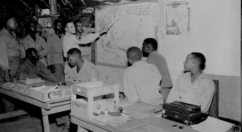 5. Negro members of the 477th Antiaircraft Artillery, Air Warning Battalion, study maps in the operations section at Oro Bay, New Guinea. November 15, 1944.