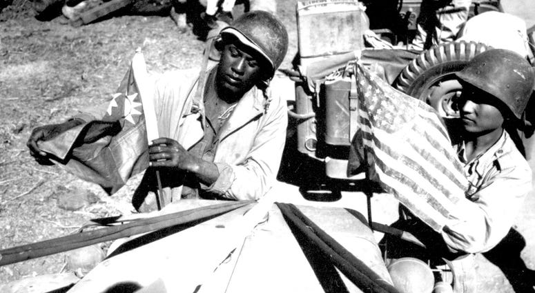 6. A U.S. Army soldier and a Chinese soldier place the flag of their ally on the front of their jeep just before the first truck convoy in almost three years crossed the China border in 1945.