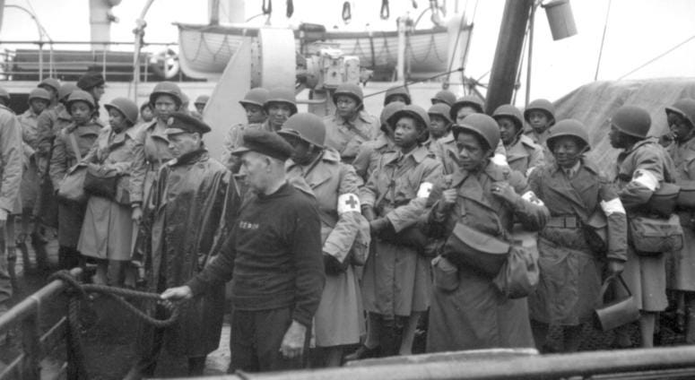 U.S. Army nurses, newly arrived, line the rail of their vessel as it pulls into port of Greenock, Scotland, in European Theater of Operations. They wait to disembark as the gangplank is lowered to the dock. August 15, 1944.