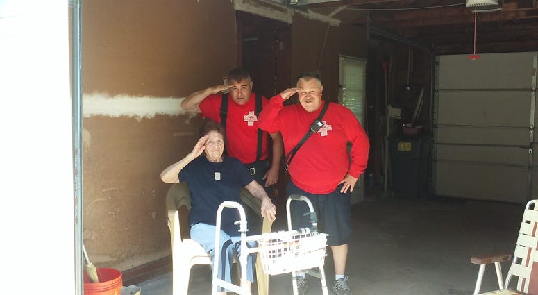 Firefighters Ronnie Giroux (L) and Jessie Peters (R) stand behind 97-year-old Ellen Peoples. The two had helped her put up her American flag.