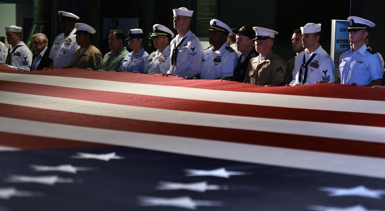 Members of the United States Armed Forces and war veterans join to hold a 100 ft. American flag during the Annual Memorial Day Ceremony aboard the Intrepid Sea, Air & Space Museum in New York, NY.