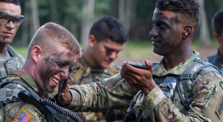 An infantryman from covers fellow soldier with camouflage paint. They preparing for a live fire exercise during a National Guard Bureau-sponsored exercise uniting approximately 5,000 service members from 13 states and five coalition countries