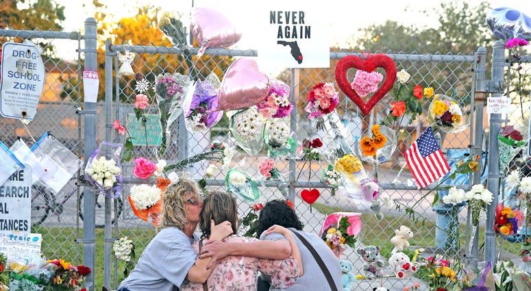 Shari Unger kisses Melissa Goldsmith as Giulianna Cerbono lights candles at a memorial at Marjory Stoneman Douglas High School on Sunday, February 18, 2018. Shari Unger kisses Melissa Goldsmith as Giulianna Cerbono lights candles at a memorial at Marjory Stoneman Douglas High School on Sunday, February 18, 2018.