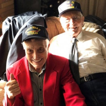 Brothers Ed and Ted Sikora pose for a photo wearing World War II veteran caps