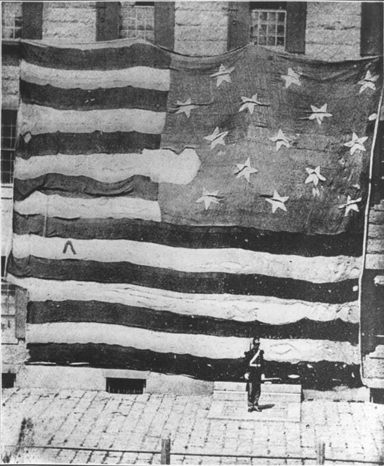 The first photograph of the Star Spangled Banner, which survived the bombardment of Ft McHenry, on display at the Boston Navy Yard in 1873.