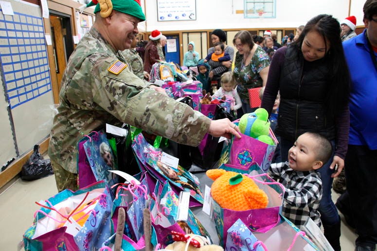 This Dec. 3, 2019, photo shows Alaska National Guard Staff Sgt. Joseph Sallaffie handing a gift bag to Corban Jimmy while Marlene Black looks on during Santa's visit to Napakiak, Alaska. This Dec. 3, 2019, photo shows Alaska National Guard Staff Sgt. Joseph Sallaffie handing a gift bag to Corban Jimmy while Marlene Black looks on during Santa's visit to Napakiak, Alaska.