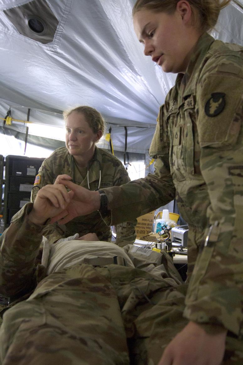 Maj. Andrea Hickman, of Des Moines, Iowa, a family medicine physician, and Pfc. Madison Huggins, check a simulated casualty for hemorrhaging in their initial trauma treatment during training. Hickman