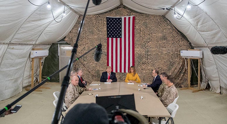 President Donald Trump, accompanied by National Security Adviser John Bolton, third from left, first lady Melania Trump, fourth from right, US Ambassador to Iraq Doug Silliman, third from right, and senior military leadership, speaks to members of the med President Donald Trump, accompanied by National Security Adviser John Bolton, third from left, first lady Melania Trump, fourth from right, US Ambassador to Iraq Doug Silliman, third from right, and senior military leadership, speaks to members of the med