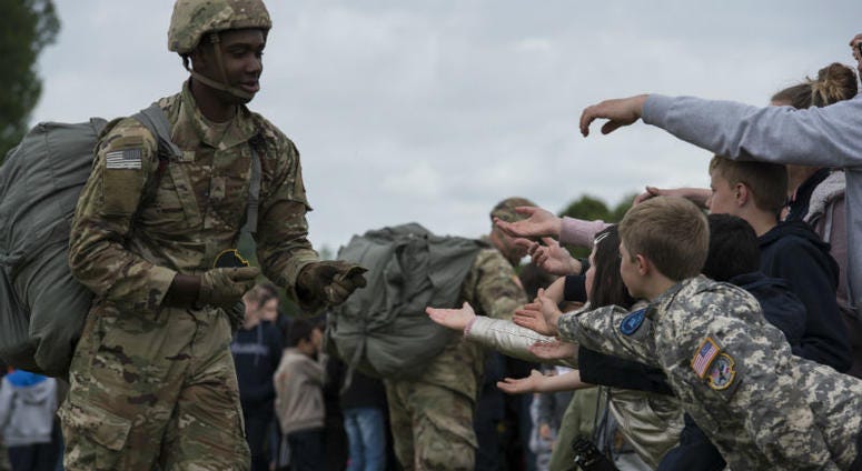 U.S. static-line paratrooper gives his military service patches to the eager hands of French boys and girls. Over 1,000 U.S. paratroopers participate in largest airborne operation since WWII to commemorate 75th anniversary of D-Day.
