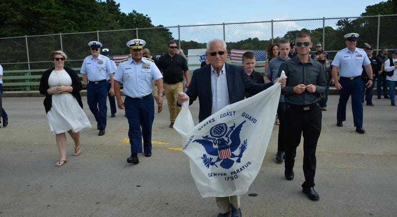 Bradley Finch crosses a Cape Cod bridge holding a Coast Guard Enslgn