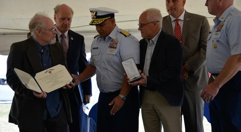 Coast Guard Adm. Andy Tiongson prepares to pose for a photo with Stephen and Bradley Finch