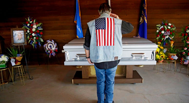 Army veteran Mike Traupman salutes the casket of World War II veteran Herman White