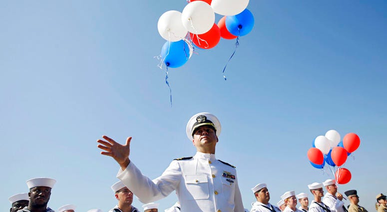 Navy Lieutenant Luke Hosman releases balloons during a funeral service for World War II veteran Herman White