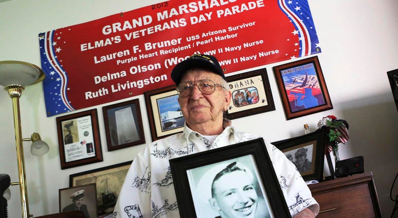 In this Nov. 17, 2016, file photo, Lauren Bruner, a survivor of the USS Arizona which was attacked on Dec. 7, 1941, holds with a 1940 photo of himself at his home in La Mirada, Calif. Divers will place the ashes of Bruner in the wreckage of his ship durin In this Nov. 17, 2016, file photo, Lauren Bruner, a survivor of the USS Arizona which was attacked on Dec. 7, 1941, holds with a 1940 photo of himself at his home in La Mirada, Calif. Divers will place the ashes of Bruner in the wreckage of his ship durin