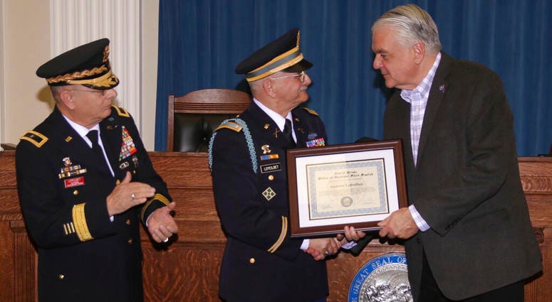In this Dec. 11, 2019, photo, Army veteran Andrew LePeilbet, center, whose platoon came under heavy fire in Vietnam in 1969, receives a certificate from Gov. Steve Sisolak, right, for a Silver Star medal