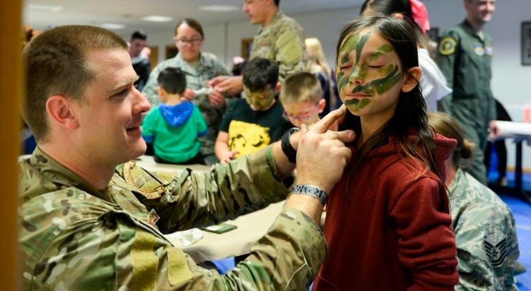 A member of the 352nd Special Operations Wing puts on camouflage paint on a child during the second annual Month of the Military Child celebration hosted by the 100th Operations Group at RAF Mildenhall, England, April 24, 2018. During the celebration, chi 352ndSpecialOperationsWing
