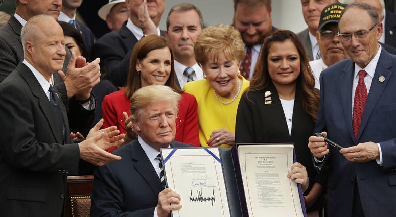 President Donald Trump holds up the Veterans Affairs Mission Act he signed during a ceremony with members of Congress, including House Veterans Affairs Committee Chairman Phil Roe, R-Tenn., and veterans in the Rose Garden at the White House. MISSIONAct